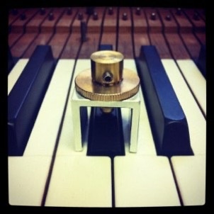 A small tool over the top of a piano sharp being used to level the piano keys. 
